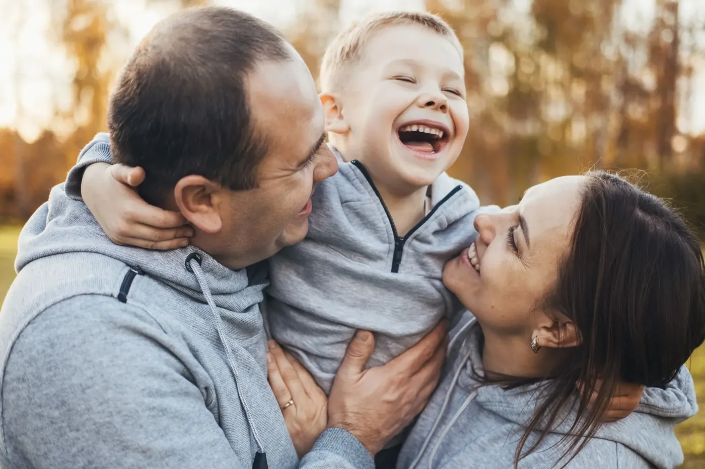 Laughing parents hugging their young son