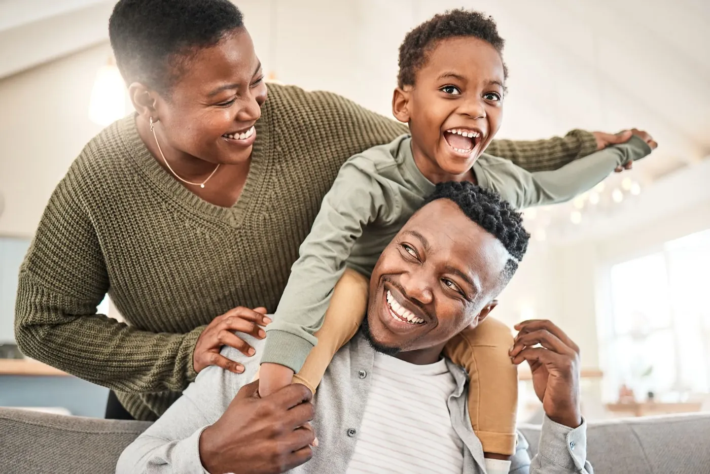 Smiling family playing together, child riding on dad's shoulders