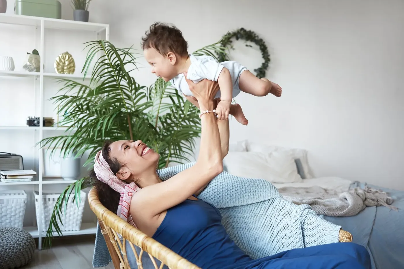 Mother lifting her baby overhead at home