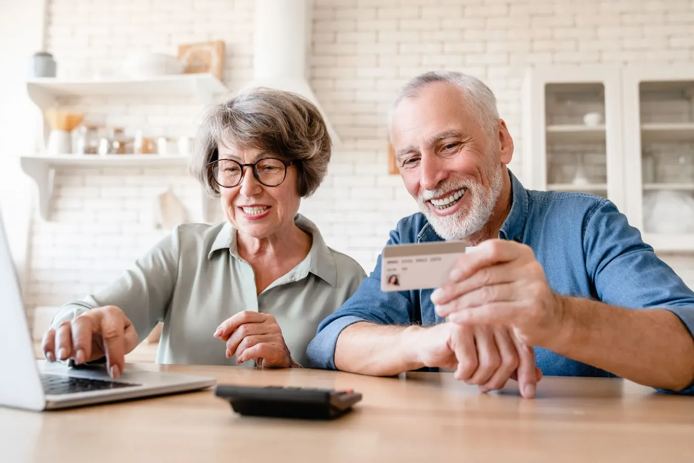 Smiling senior couple paying online at their table